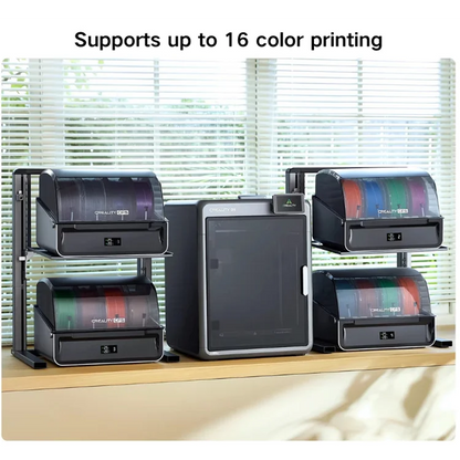A desktop 3D printer setup with four color cartridges loaded into the printer racks, shown on a wooden shelf in front of window blinds. Text at the top reads 'Supports up to 16 color printing'.
